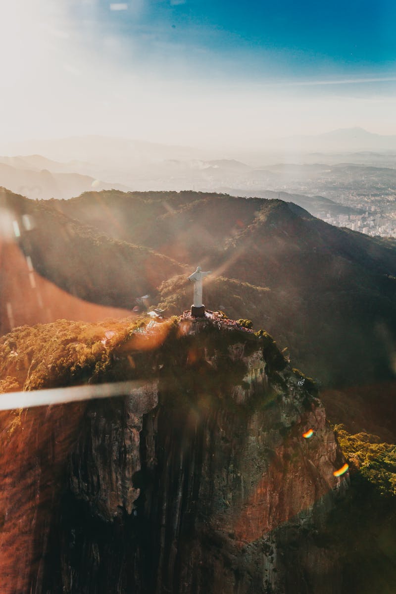 Stunning aerial view of Christ the Redeemer in Rio de Janeiro at sunrise, showcasing vibrant sunrays and breathtaking landscape.