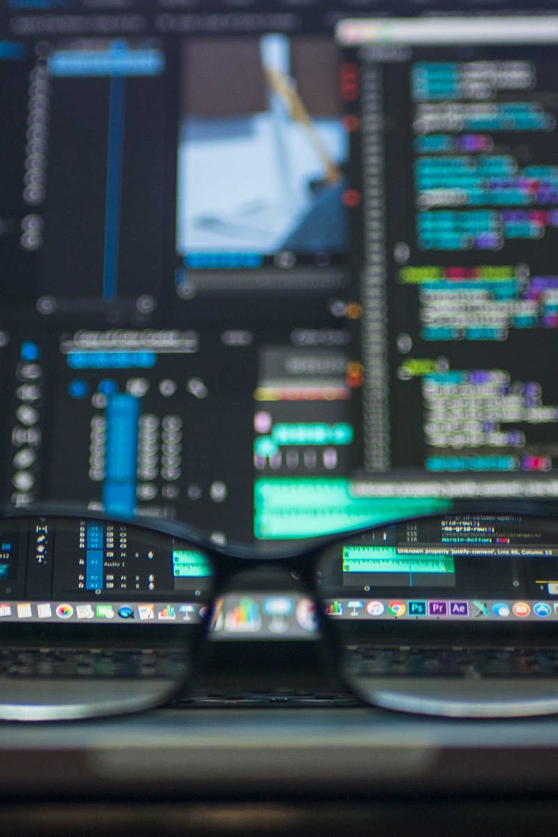 Eyeglasses reflecting computer code on a monitor, ideal for technology and programming themes.